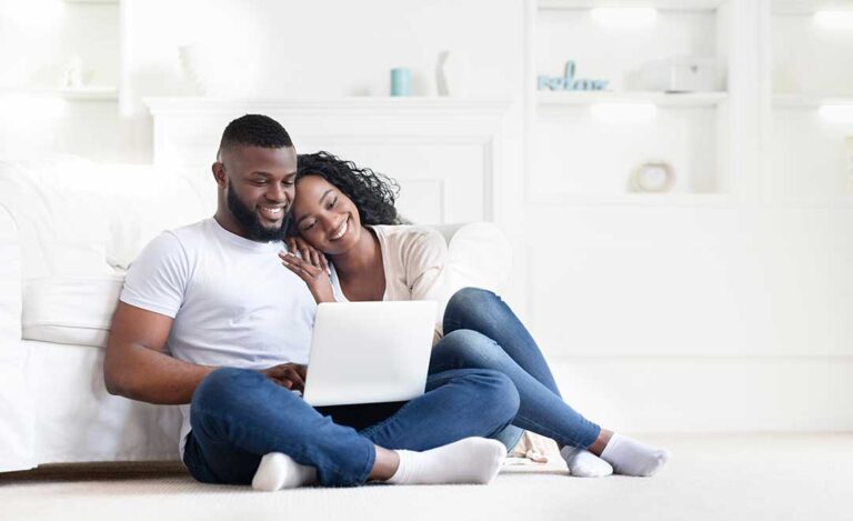 A homeowner and real estate agent reviewing a home maintenance checklist in a tidy living room.