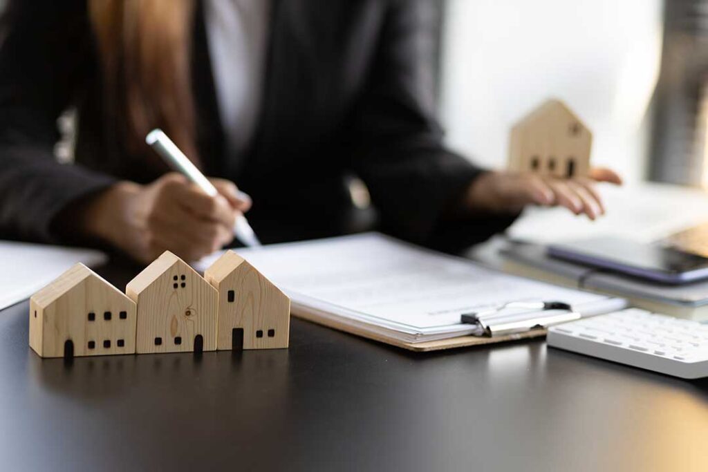A couple reviews home purchase documents with a pen and calculator at a kitchen table.