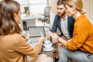 A homeowner and a real estate agent reviewing documents together at a kitchen table.