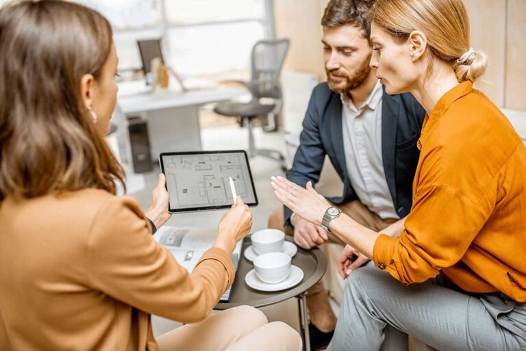 A homeowner and a real estate agent reviewing documents together at a kitchen table.