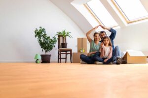 A couple reviews mortgage documents and a home budget with a lender at a kitchen table.
